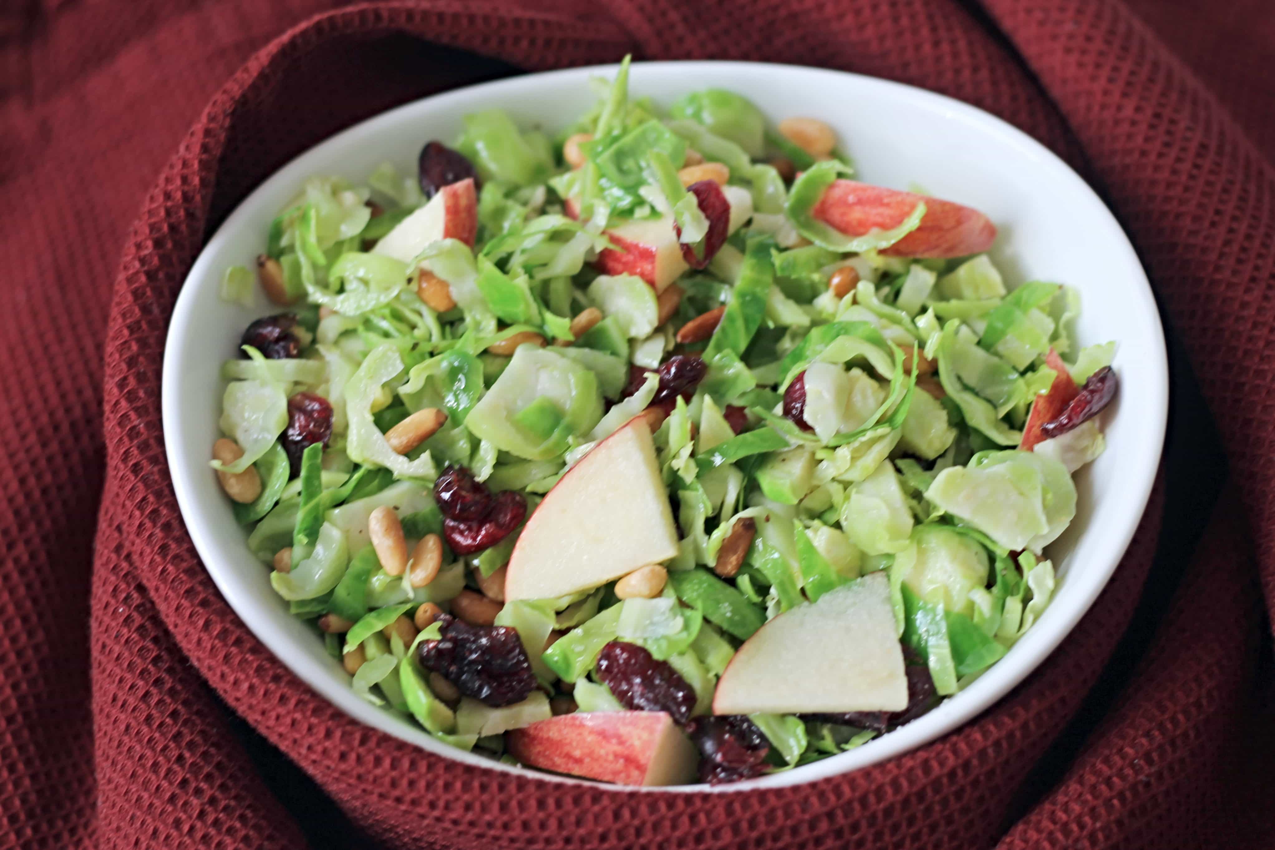 Fall Shredded Brussel Sprout Salad in white ceramic bowl on deep red napkin