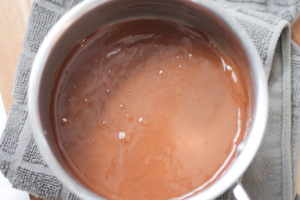 Melted chocolate in saucepan on grey kitchen towel