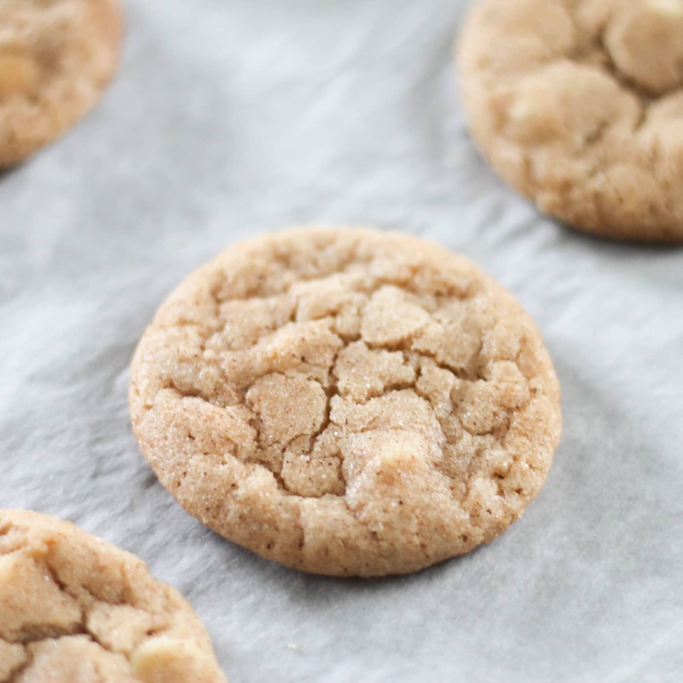Baked snickerdoodle cookies on parchment lined baking sheet.