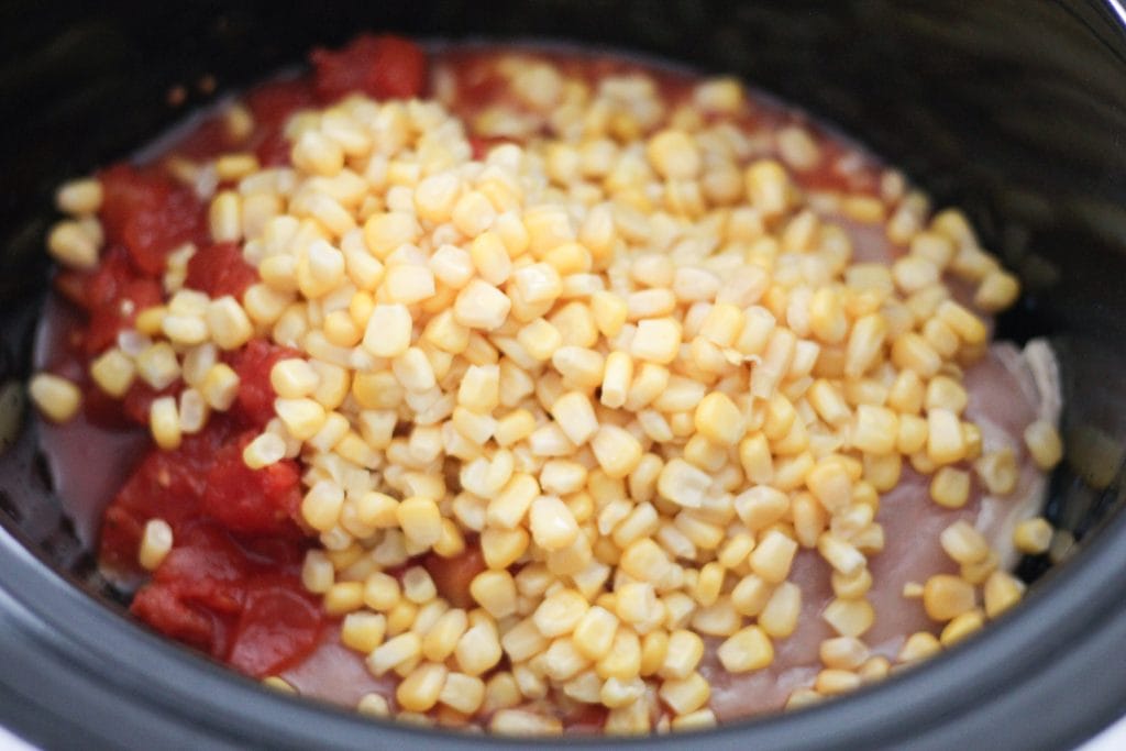 Slow cooker with ingredients for soup; corn on top.